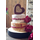 4 tier cheese cake with red decorative flowers and red raffia going round the cheese. Top tier is heart shaped cheese.