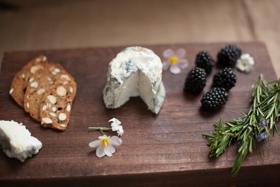 Dorstone goat cheese on wooden board with crackers and blackberries